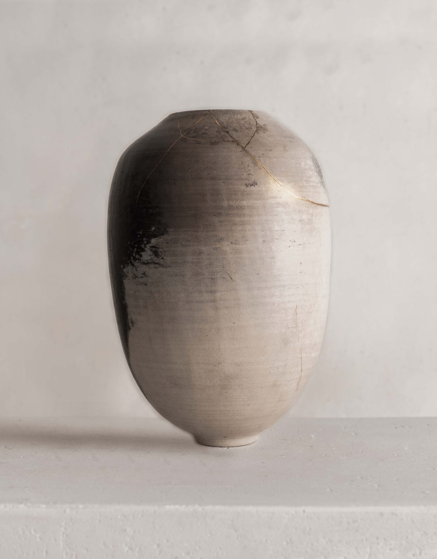 vase en grès clair, sublimé par une délicate réparation en kintsugi qui magnifie ses fissures naturelles. Ce modèle met en valeur la beauté de l'imperfection et l'élégance discrète du travail artisanal