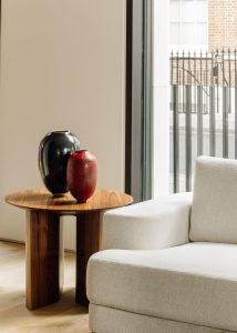 Un grand vase en poterie noire brillante et un petit vase en céramique texturée rouge, sur une table en bois minimaliste dans une salle d'exposition