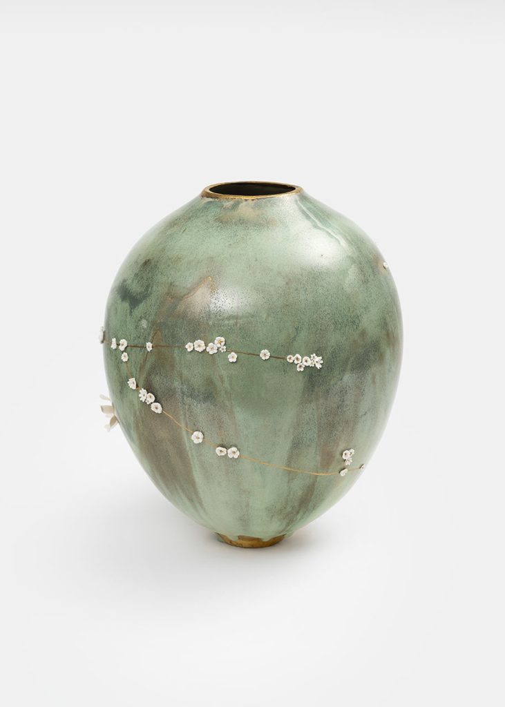 Vase kintsugi en céramique céladon vert de Karen Swami décoré de fleurs blanches en porcelaine.