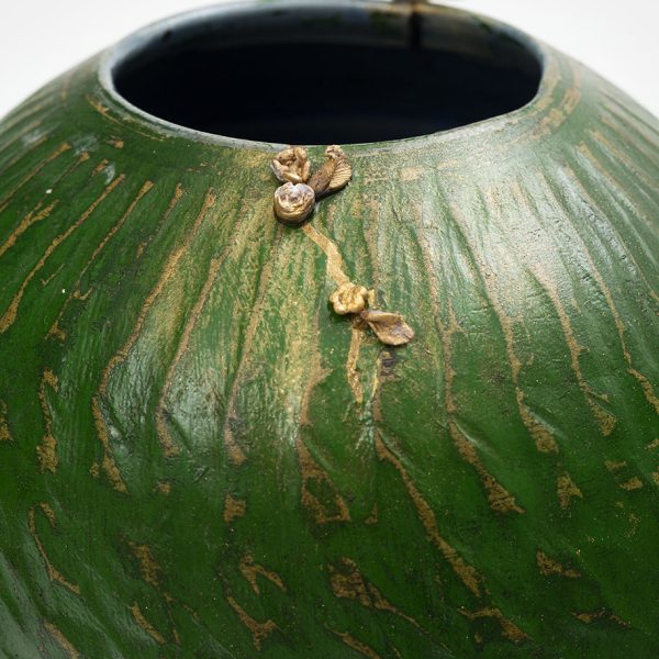 Détail d'un vase en céramique verte et or signé Karen Swami.