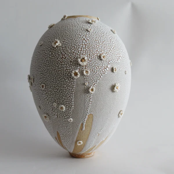 Vase blanc craquelé de Karen Swami décoré de fleurs en porcelaine sculptées.