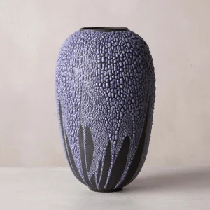 vase-glycine-ceramique-fabriquee-a-la-main-piece-unique-gres-roux-email-bombe.webp vase design, céramique contemporaine, surface craquelée violette sur fond noir mat, objet d’art puissant et texturé, réalisé en grès, pièce unique au caractère volcanique