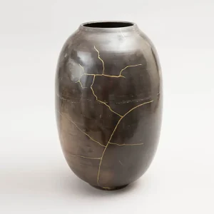 vase-kintsugi-artist-ceramiste-concu-en-france-exclusive-decoration-en-gres-qualitee-noir-aux-reflets-verts vase en céramique noir, réparé en kintsugi, lignes de fissures dorées visibles sur la surface lisse, pièce unique en grès fait main, technique japonaise de réparation, objet d’art contemporain, design luxe, céramiste français, décoration haut de gamme