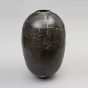 vase-kintsugi-ceramiques-francaises-artisanales-luxe-contemporain-objet-unique-ombre-poli vase en céramique, noir brillant réparé en kintsugi, fissures dorées visibles sur une surface lisse et bombée, pièce d’art en grès tourné, céramique japonaise contemporaine, objet décoratif unique, création faite main, design luxe